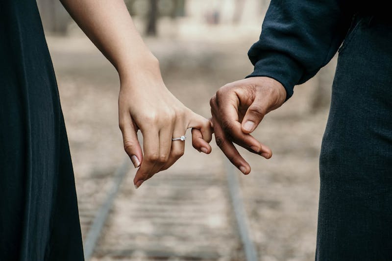 Two hands gently intertwined in a delicate, intimate gesture of connection and warmth